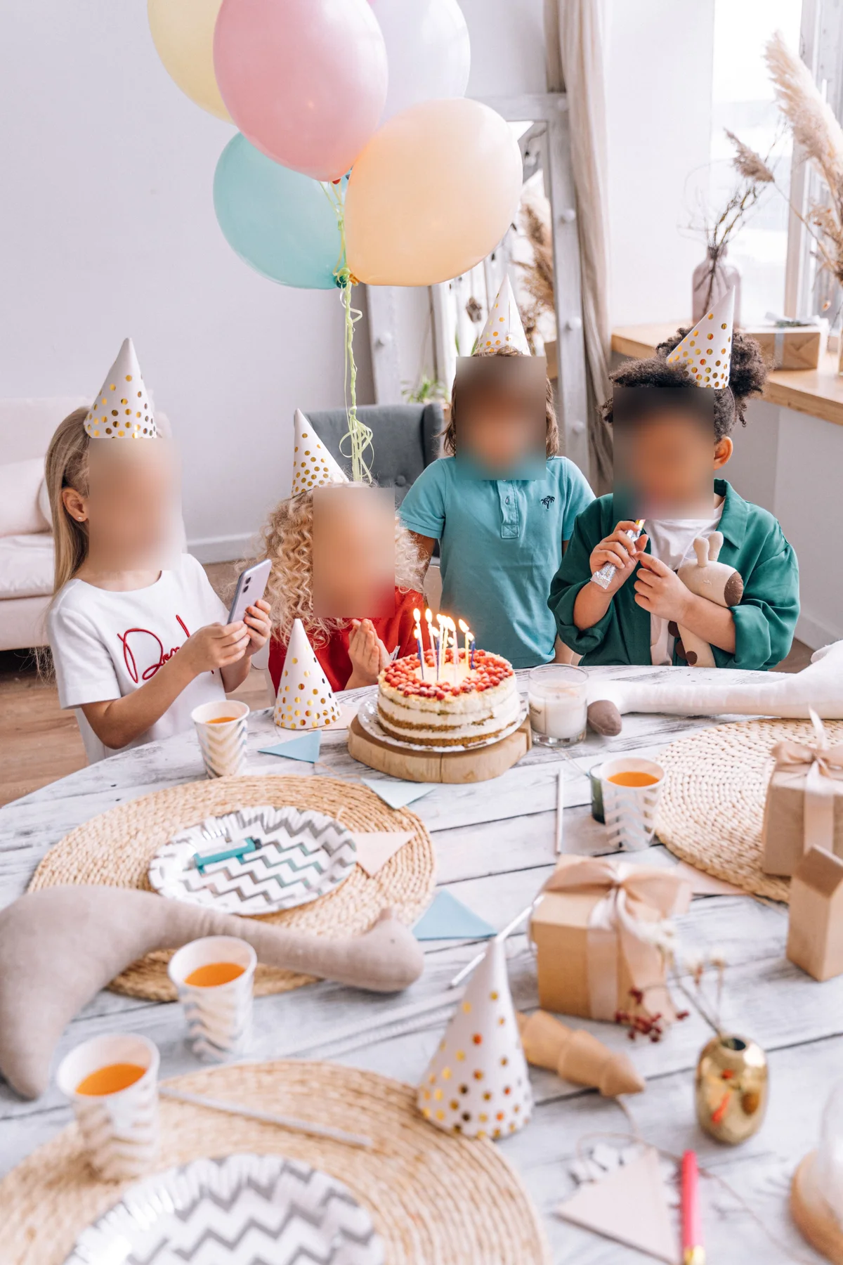 The same birthday photo with all four children's faces blurred, the cake and party unchanged